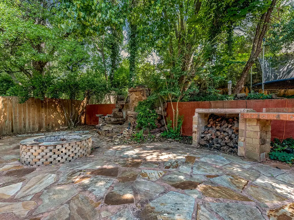 Flagstone patio with a sunken fire pit and stacked firewood storage